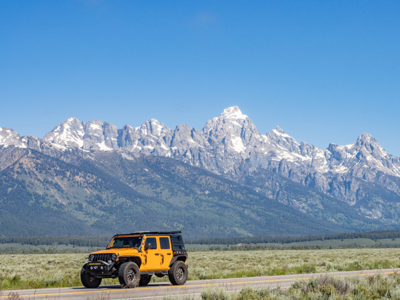 Yellow Jeep Wrangler with mountain range in the background