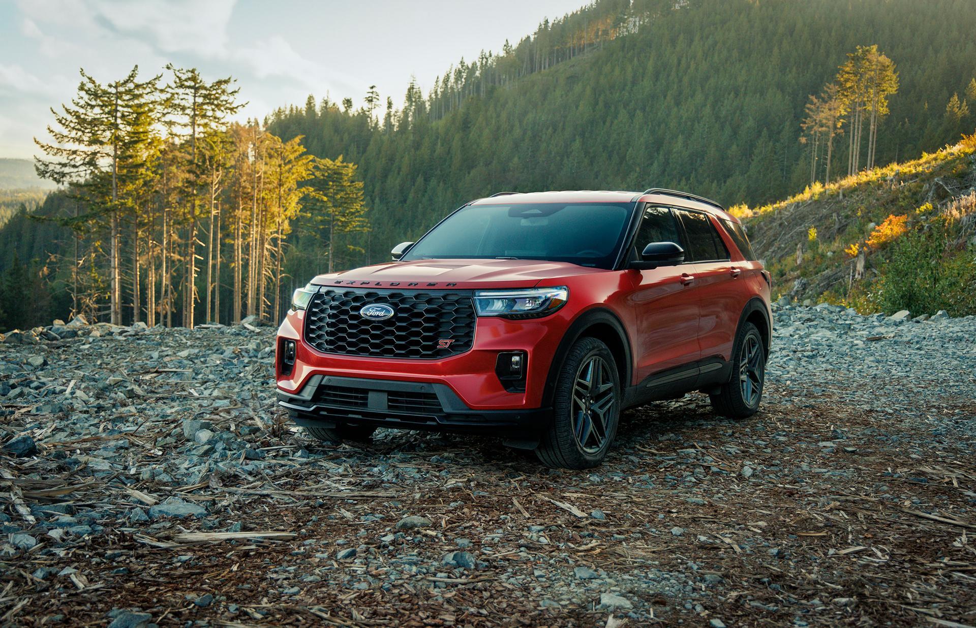 A red ford explorer sitting parked in a forest.